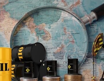A magnifying glass focused on a world map, positioned behind industrial oil barrels and a pumpjack.