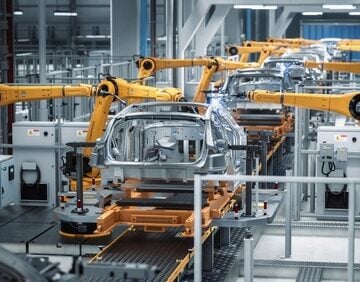 An automated industrial production line for manufacturing vehicles which features multiple robotic arms engaged in welding or assembly processes on vehicle frames.