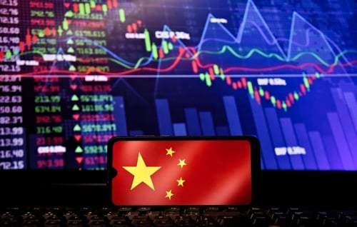 The Chinese national flag overlaid on a smartphone screen against a backdrop of volatile financial data and trading charts. The Chinese national flag overlaid on a smartphone screen against a backdrop of volatile financial data and trading charts.