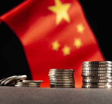 Chinese,Coins,With,The,Flag,Of,The,People's,Republic,Of Stacks of Yuan coins in front of the national flag of the People's Republic of China.