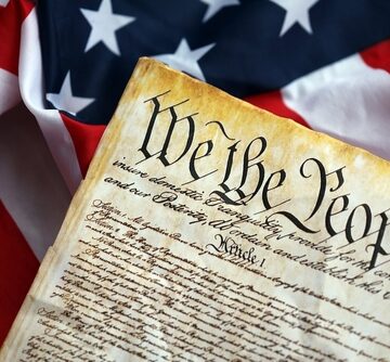 A parchment replica of the U.S. Constitution's preamble resting on a United States flag. A parchment replica of the U.S. Constitution's preamble resting on a United States flag.