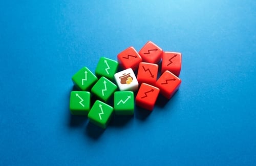 Green dice with upward arrows, and red dice with downward arrows surrounding a center die with a money bag image.