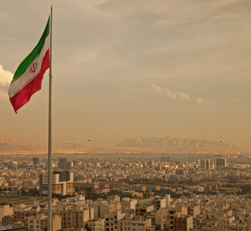 The flag of Iran flying over the Tehran skyline. The flag of Iran flying over the Tehran skyline.