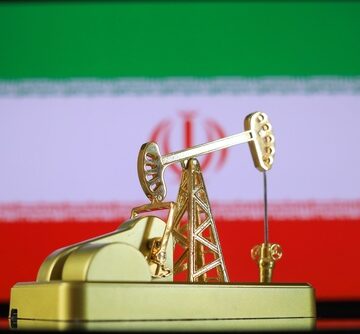 A miniature golden oil pump against the backdrop of the Iranian flag. A miniature golden oil pump against the backdrop of the Iranian flag.