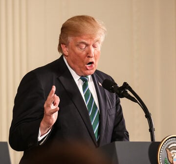 Donald Trump speaking at a podium in Washington, DC.