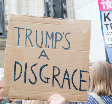 A handwritten protest sign that reads "Trump's A Disgrace" held by an individual during a demonstration in central London. A handwritten protest sign that reads "Trump's A Disgrace" held by an individual during a demonstration in central London.