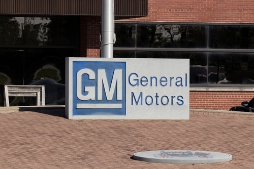 The General Motors (GM) logo on a sign outside a brick building. The General Motors (GM) logo on a sign outside a brick building.