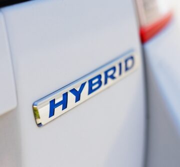 A close-up view of a hybrid car logo – these vehicles use both an internal combustion engine and an electric motor. A close-up view of a hybrid car logo – these vehicles use both an internal combustion engine and an electric motor.