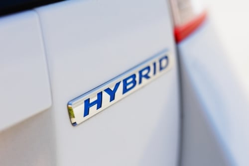A close-up view of a hybrid car logo – these vehicles use both an internal combustion engine and an electric motor. A close-up view of a hybrid car logo – these vehicles use both an internal combustion engine and an electric motor.