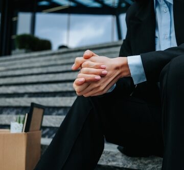 A man sitting on stairs next to a cardboard box of belongings, wringing his hands together. A man sitting on stairs next to a cardboard box of belongings, wringing his hands together.