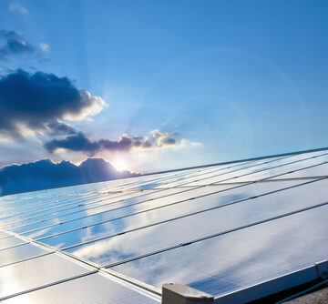 A large array of rooftop photovoltaic solar panels reflecting the blue sky and sunlit clouds. A large array of rooftop photovoltaic solar panels reflecting the blue sky and sunlit clouds.