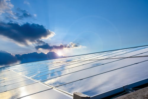 A large array of rooftop photovoltaic solar panels reflecting the blue sky and sunlit clouds. A large array of rooftop photovoltaic solar panels reflecting the blue sky and sunlit clouds.
