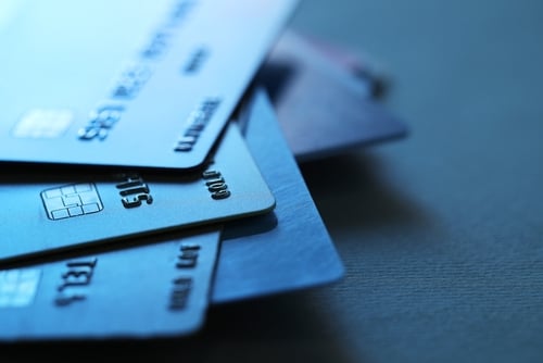 A pile of credit cards against a blue table. A pile of credit cards against a blue table.