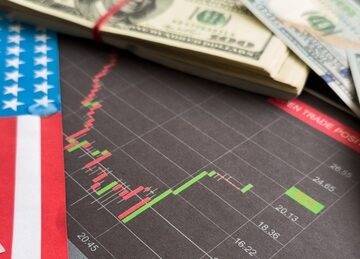 Concept image using the U.S. flag, U.S. dollar bills, and a candlestick chart. Concept image using the U.S. flag, U.S. dollar bills, and a candlestick chart.