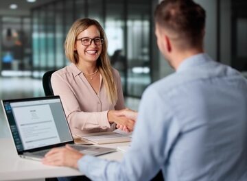 Two professionals shaking hands across a table during a meeting. Two professionals shaking hands across a table during a meeting.
