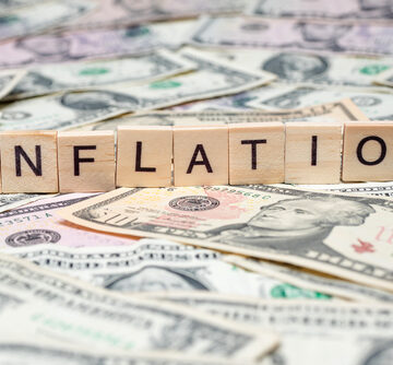 A row of scrabble pieces spelling the word "Inflation" sitting atop a mass of U.S. currency. A row of scrabble pieces spelling the word "Inflation" sitting atop a mass of U.S. currency.