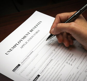 Close-up of a person filling out an unemployment benefits application form. Close-up of a person filling out an unemployment benefits application form.