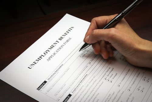 Close-up of a person filling out an unemployment benefits application form.