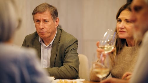 A group of friends sharing a moment, talking and enjoying glasses of white wine at a social gathering.