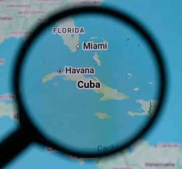 Magnified,Map,Showing,Cuba,And,Nearby,Florida,With,Overlay,Text A magnifying glass view of a map showing Cuba and nearby Florida.
