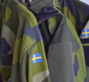 Military,Uniform,Of,The,Swedish,Army.swedish,Flag,On,The,Sleeve. A Swedish Army M90 Splinter camo field jacket featuring a distinct Swedish flag patch on the sleeve.