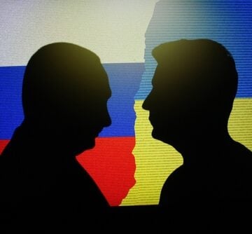 Silhouettes of Russian President Vladimir Putin and Ukrainian President Volodymyr Zelenskyy against their respective national flags.