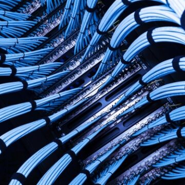 A view of cabling within a data center, neatly organized and bundled together to manage connectivity efficiently. A view of cabling within a data center, neatly organized and bundled together to manage connectivity efficiently.