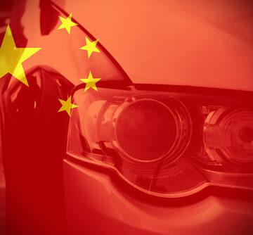 Close-up view of a car headlight overlaid with the Chinese flag. Close-up view of a car headlight overlaid with the Chinese flag.