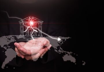 Concept illustration features a businessman's hands holding a cracked bank icon overlaid on a digital world map, with a downward-trending arrow symbolizing recession or market decline.