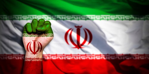 The flag of Iran painted on a male fist – representing the concept of conflict – with the Iranian flag in the background. The flag of Iran painted on a male fist – representing the concept of conflict – with the Iranian flag in the background.