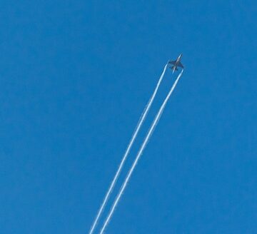 A fighter jet leaving two prominent contrails against a clear blue sky. A fighter jet leaving two prominent contrails against a clear blue sky.