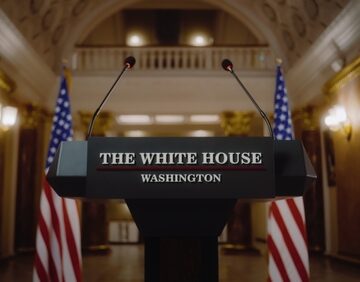 A White House podium – designed for presidential or official government press conferences – which features American flags on both sides and two microphones. A White House podium – designed for presidential or official government press conferences – which features American flags on both sides and two microphones.