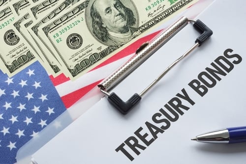A clipboard labeled "Treasury Bonds" sits atop a U.S. flag and U.S. currency.