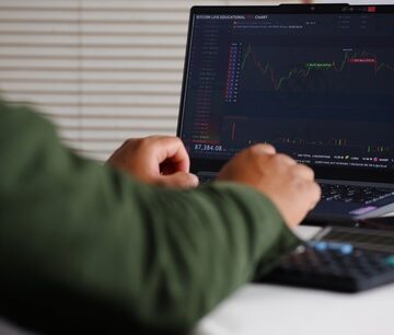 A person analyzing a financial candlestick chart on a laptop screen, likely tracking financial markets like stocks, forex, or cryptocurrency. A person analyzing a financial candlestick chart on a laptop screen, likely tracking financial markets like stocks, forex, or cryptocurrency.