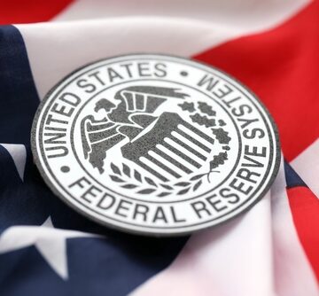 The official emblem of the Federal Reserve System resting on an American flag. The official emblem of the Federal Reserve System resting on an American flag.
