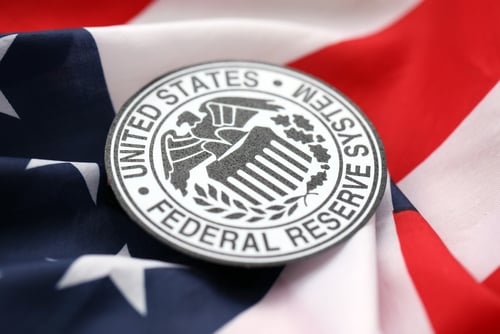 The official emblem of the Federal Reserve System resting on an American flag. The official emblem of the Federal Reserve System resting on an American flag.