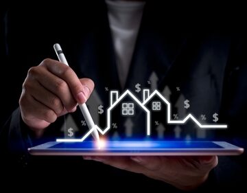Graphic overlay of person using tablet along with housing symbols, dollar signs, and growth trends highlights.