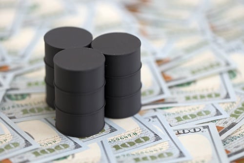 Miniature barrels of oil on a tabletop covered with U.S. $100 dollar bills. Miniature barrels of oil on a tabletop covered with U.S. $100 dollar bills.