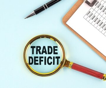 Financial concept featuring a magnifying glass highlighting the text "TRADE DEFICIT". Financial concept featuring a magnifying glass highlighting the text "TRADE DEFICIT".