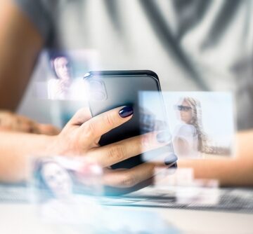 Concept image of a futuristic holographic user interface projected from a smartphone, with floating, transparent digital windows, profiles, or media tiles hovering in mid-air right above the device. Concept image of a futuristic holographic user interface projected from a smartphone, with floating, transparent digital windows, profiles, or media tiles hovering in mid-air right above the device.