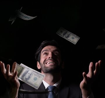 A gleeful man celebrating financial success by throwing U.S. dollar bills into the air. A gleeful man celebrating financial success by throwing U.S. dollar bills into the air.