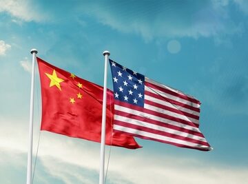 The national flags of the People's Republic of China (left) and the United States of America (right) flying side-by-side against a blue sky. The national flags of the People's Republic of China (left) and the United States of America (right) flying side-by-side against a blue sky.
