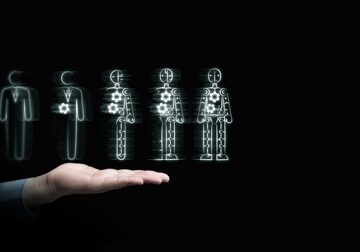 A hand holds a human figure that is progressively transforming into a robot. A hand holds a human figure that is progressively transforming into a robot.