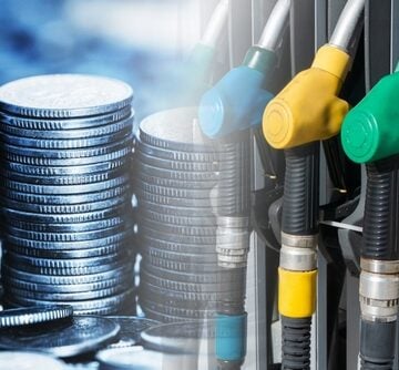 Image illustrates the financial impact of fuel costs, juxtaposing stacks of coins with fuel dispenser nozzles. Image illustrates the financial impact of fuel costs, juxtaposing stacks of coins with fuel dispenser nozzles.