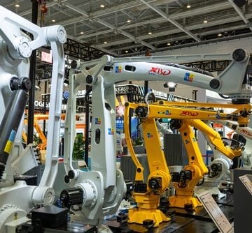 A display of multi-axis industrial robotic arms at a manufacturing and automation technology exhibition, featuring heavy-duty white and yellow articulated robots designed for high-precision assembly, material handling, or welding. A display of multi-axis industrial robotic arms at a manufacturing and automation technology exhibition, featuring heavy-duty white and yellow articulated robots designed for high-precision assembly, material handling, or welding.