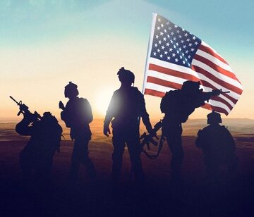 Us,Soldiers,Stand,Together,With,An,American,Flag,During,A THE NORMALCY OF AMERICAN WARS