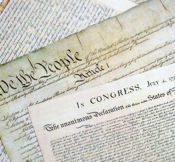 The two foundational texts of the United States government: the Constitution of the United States (top/background, featuring the famous "We the People" heading and "Article I") and the Declaration of Independence (foreground, headed "IN CONGRESS, July 4, 1776" and "The unanimous Declaration of the thirteen United States of America") The two foundational texts of the United States government: the Constitution of the United States (top/background, featuring the famous "We the People" heading and "Article I") and the Declaration of Independence (foreground, headed "IN CONGRESS, July 4, 1776" and "The unanimous Declaration of the thirteen United States of America")