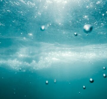 An underwater view of bubbles and water texture in a deep blue ocean.