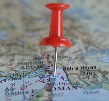 A red pushpin on a map marks the Strait of Hormuz, a critical chokepoint situated between the Persian Gulf and the Gulf of Oman.