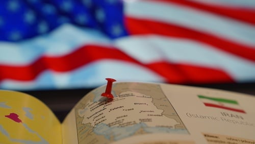 Image of a pushpin placed on a map of Iran with an American flag in the background. Image of a pushpin placed on a map of Iran with an American flag in the background.